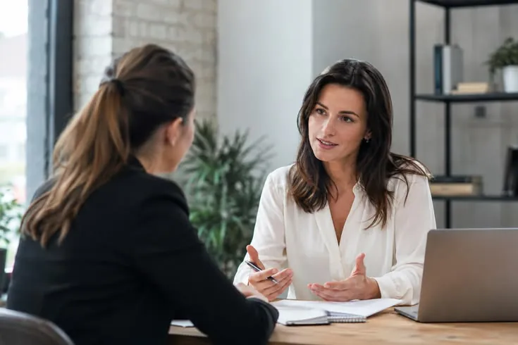 Duas mulheres conversando em uma reunião, em foto ilustrativa